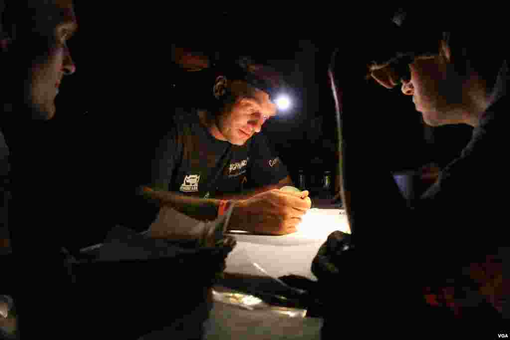 Henrik Rasmussen and other members of Car 54, the Danish team, plot the next day&#39;s Rhino Charge by the light of a head lamp and bonfire, June 1, 2012. (VOA/Jill Craig)