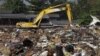 FILE - A man sifts through pile of garbage, left over after the flood, at a temporary dump site on the outskirts of Bangkok, Thailand, Dec. 20, 2011.