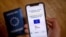 A picture taken on June 29, 2021 in Paris shows a passport behind a mobile phone whose screen bears a EU Digital COVID certificate.