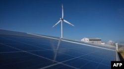 ແຟ້ມພາບ - ການຕິິດຕັ້ງແຜ່ນເກັບພະລັງແສງຕາເວັນທ ເຫັນໄດ້ຢູ່ໃກ້ກັບກັງຫັນລົມ ຢູ່ທີ່ຟາມລົມ the Phu Lac ໃນແຂວງ ບິນ ທວນ ທາງພາກໃຕ້ຂອງຫວຽດນາມ, ວັນທີ 23 ເມສາ 2019. 