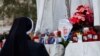 A nun prays as candles and flowers are placed at the base of the statue of the late Pope John Paul II outside the Gemelli Hospital where Pope Francis is admitted for treatment, in Rome, Italy, Feb. 23, 2025. 