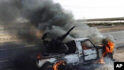 A pro-Moammar Gadhafi anti-aircraft machine gun is burned by Libyan rebels during a battle, in the town of Brega, east of Libya, March 2, 2011 