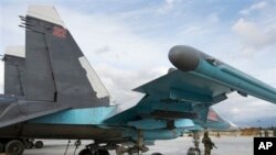 Un soldat russe monte la garde devant un bombardier Su-34 stationné à la base aérienne russe de Hemeimeem en Syrie. 20 janvier 2016.
(AP Photo/Vladimir Isachenkov)