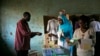 A party observer (l) asks to help a Kenyan lady cast her ballots at a polling station in the Kibera slum in a general election in Nairobi, March 4, 2013. 