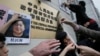 香港民众在北京驻香港机构中联办前高举铜锣湾书店老板桂民海的肖像，要求中国政府释放桂民海。（2016年1月19日）