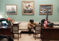 FILE - Supporters of U.S. President Donald Trump sit inside the office of U.S. Speaker of the House Nancy Pelosi as they protest inside the U.S. Capitol in Washington, Jan. 6, 2021.