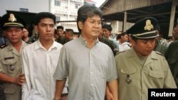 រូបឯកសារ៖ លោក រីឆាដ គិរី គីម (Richard Kiri Kim) (រូបកណ្តាលពាក់វ៉ែនតា) អតីត​មេដឹកនាំ​ចលនា​កងទ័ព​សេរីជាតិ​កម្ពុជា ដើរចេញ​ពី​សាលា​ដំបូង​រាជធានី​ភ្នំពេញ​កាលពី​ថ្ងៃទី២២ ខែមិថុនា ឆ្នាំ២០០១។ 