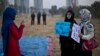 FILE - A Pakistani student uses her mobile phone to take a picture of her friends holding banners prior to a protest in Islamabad, Pakistan, Dec. 19, 2014. Some activists say that the Pakistani government has been silencing critics by selectively reporting their social media posts to platforms like Facebook and Twitter as unacceptable content.