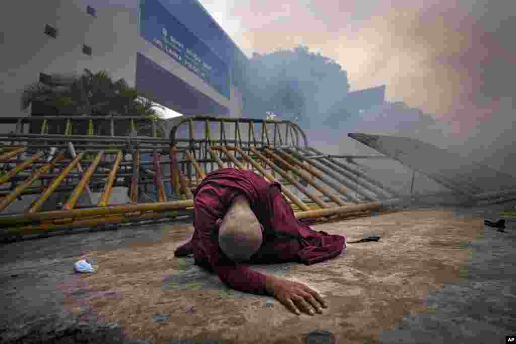 A Buddhist nun falls next to a barricade after inhaling tear gas during a protest outside police headquarters in Colombo, Sri Lanka, June 9, 2022.