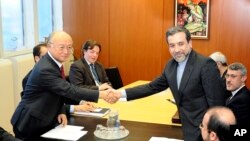 Deputi Menlu Iran, Abbas Araghchi (kanan) berjabat tangan dengan Direktur IAEA, Yukiya Amano di Wina hari Senin (28/10).