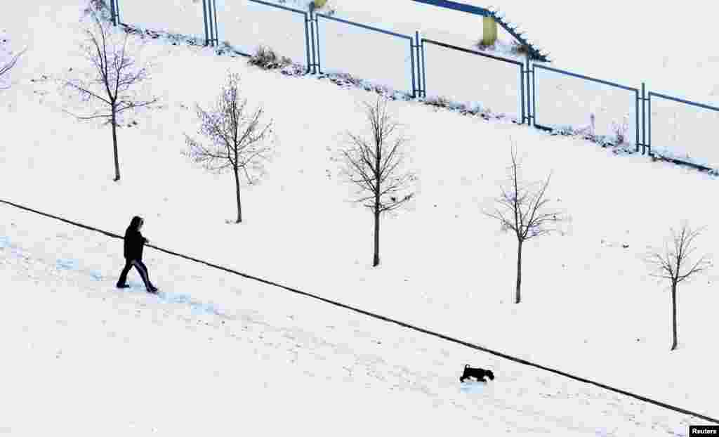 A man with a dog walks during the first snowfall in Minsk, Belarus.