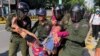 A woman is carried by police officers after security guards broke up a small protest near the Chinese embassy opposing alleged plans to boost Beijing's military presence in the country, in Phnom Penh, Cambodia October 23, 2020. (REUTERS/Heng Mengheang)