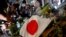 Yon drapo Japone bo kote yon paket bouke fle moun depoze nan lye kote ansyen Premye Minis Shinzo Abe te mouri pa bal pandan li tap mennen kanpay pou eleksyon palmante yo, nan vil Nara, rejyon wes Japon, 8 Jiye 2022. 