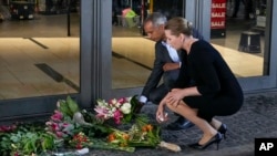 Danish Prime Minister Mette Frederiksen, foreground and Minister of justice Mattias Tesfaye lay flowers at the entrance of the Field's shopping center in Copenhagen, Denmark, July 4, 2022.