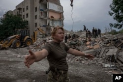 Pripadnica ukrajinskih oružanih snaga nalaže novinarima da se pomjere dalje od mjesta ruskog raketnog udara na stambenu zgradu u Časiv Jaru, region Donjetska, Istočna Ukrajina, 10. jula 2022.