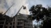 A rescue worker sprays water on an apartment building destroyed in a missile strike, amid Russia's invasion of Ukraine, in Kyiv, June 26, 2022. 