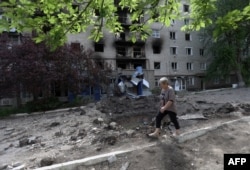 រូបឯកសារ៖ ស្ត្រីម្នាក់ដើរកាត់អគារដែលត្រូវបានបំផ្លាញនៅក្នុងភូមិ Siversk នៃតំបន់ Donetsk កាលពីថ្ងៃទី ២៣ ខែមិថុនា ឆ្នាំ ២០២២ ខណៈការឈ្លានពានរបស់រុស្ស៊ីនៅតែបន្តកើតឡើង។