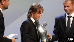 Le milieu de terrain du Real Madrid Croatie Luka Modric, au centre, reçoit le titre de Joueur de l'année de l'UEFA lors du tirage au sort du tournoi de football de l'UEFA Champions League au Grimaldi Forum à Monaco le 30 août 2018.
