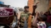 FILE - A policeman argues with a supporter of opposition leader Kizza Besigye at the gates of his party headquarters, before police who had surrounded it raided the building, in Kampala, Uganda, Feb. 19, 2016. 