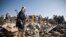 A Houthi Shiite fighter stands guard as people search for survivors under the rubble of houses destroyed by Saudi airstrikes near Sanaa Airport, Yemen, Thursday, March 26, 2015