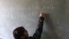 FILE - A Syrian refugee girl writes "we miss Syria too much" on the chalkboard in her classroom in Majdel Anjar in Bekaa Valley December 27, 2012.