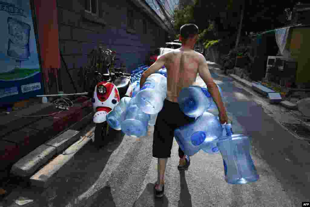 2018年7月27日，一名送水员在北京的一条小巷里收集空瓶。