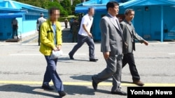 제3국을 통해 북한에 들어갔던 김모(52·황색 옷) 씨가 11일 판문점을 통해 한국으로 귀환하고 있다.