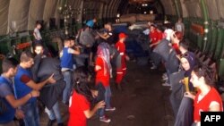 تصویر خبرگزاری دولتی سوریه که اعضای هلال احمر سوریه را در حال تخلیه هواپیمای روسی در شهر لاذقیه نشان می دهد - ۱۲ سپتامبر ۲۰۱۵