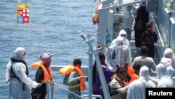 Migrants walk aboard the Italian navy ship Scirocco during a rescue operation about 40 nautical miles off the coast of Libya in this handout picture released on June 14, 2014 by the Italian Marina Militare. 
