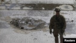 Seorang tentara NATO berdiri di lokasi bom bunuh dire di Kabul, Afghanistan, 11 Oktober 2015. (REUTERS/Mohammad Ismail)