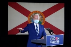 FILE - The Florida state flag hangs behind Democratic presidential candidate former Vice President Joe Biden as he speaks at Southwest Focal Point Community Center in Pembroke Pines, Fla., Oct. 13, 2020.