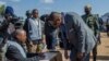 President Peter Mutharika gets instructions on how to vote from a presidisng officer, in Thyolo district. (Lameck Masina/VOA) 