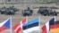 FILE - Flags wave in front of soldiers taking positions with their army vehicles during the NATO Noble Jump exercise on a training range near Swietoszow Zagan, Poland, June 18, 2015.