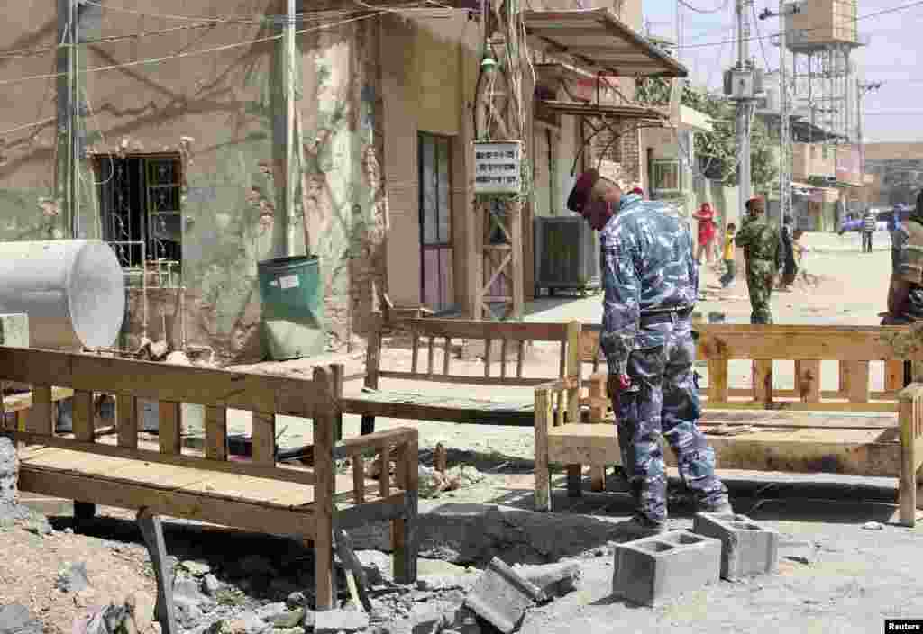 An Iraqi policeman inspects the site of a suicide bombing attack at a coffee shop in the city of Baquba, July 2, 2013. 