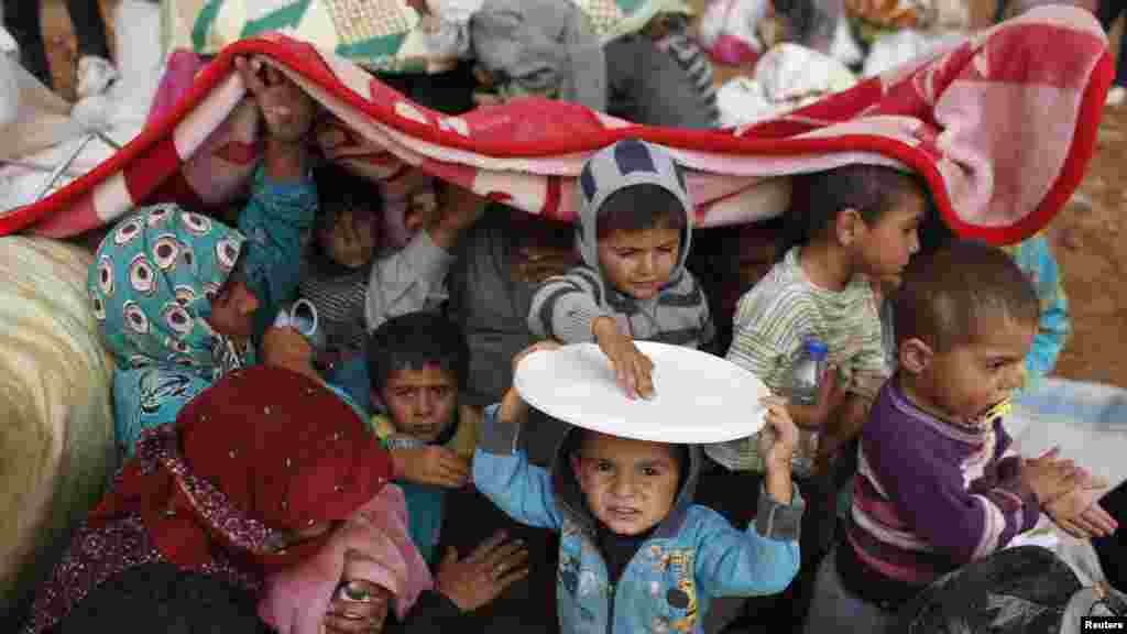 La couverture et les assiettes sont les seuls abris contre la pluie pour ces réfugiés kurdes syriens traversant la frontière pour la Turquie voisine dans la ville de Kobani, (Photo, le 2 octobre 2014). 