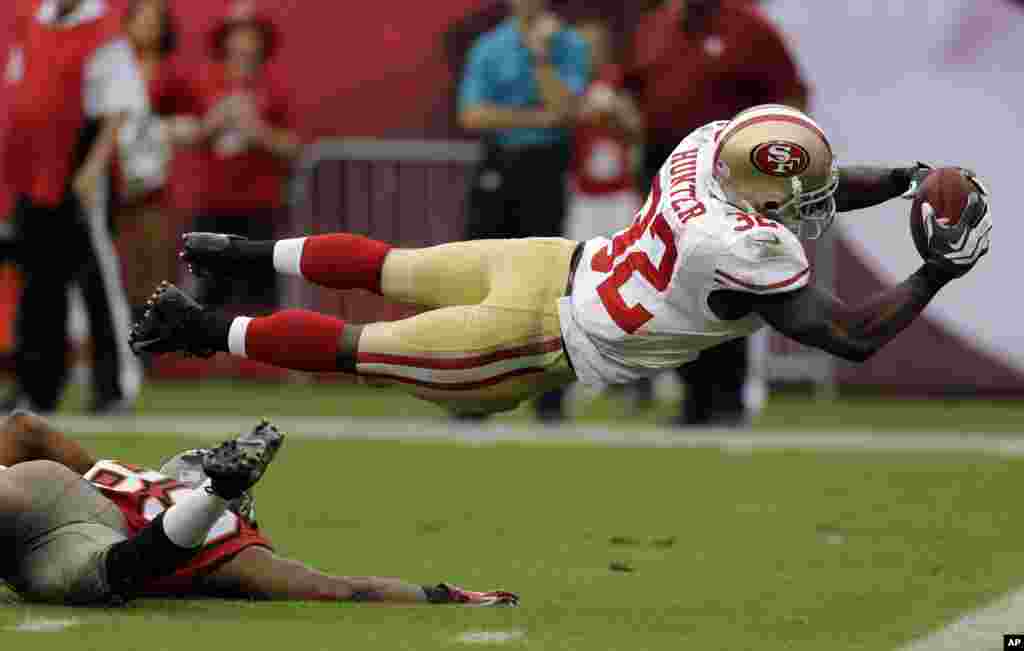San Francisco 49ers&#39; Kendall Hunter (32) dives into the end zone to score after picking up a fumble by Tampa Bay Buccaneers&#39; Russell Shepard during the fourth quarter of an NFL football game in Tampa, Florida, USA, Dec. 15, 2013.