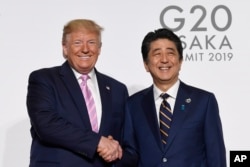 美国总统朗普与日本首相安倍在G20大阪峰会上握手。