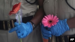 6月26日，印度孟买亚洲最大的贫民窟一个免费的医疗营关闭时，保安人员手持人们为表达谢意而送给他们的花。