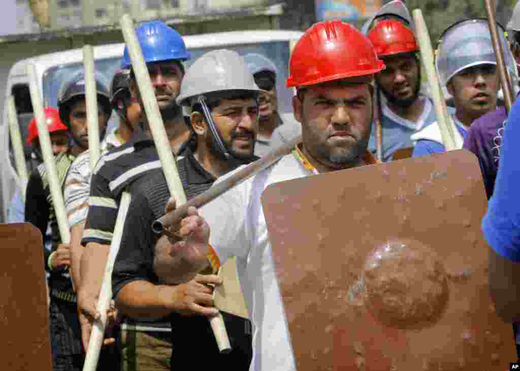 Para pendukung Presiden Mesir Mohammed Morsi memegang tongkat dan memakai alat pelindung dalam pelatihan di luar masjid Rabia el-Adawiya dekat istana kepresidenan (2/7). (AP/Amr Nabil)