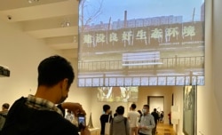 民主派前油尖旺区议员陈嘉朗(拿手机者)在M+博物馆参观艾未未录像作品《长安街》，他认为艺术品不应与国家安全扯上关系 (美国之音/汤惠芸)