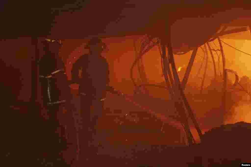 Para petugas pemadam kebakaran mencoba mengontrol api di dalam sebuah pabrik garmen di Gazipur, Bangladesh (9/10).