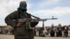 FILE - A member of the Taliban insurgent and other people stand at the site during the execution of three men in Ghazni Province, Afghanistan, April 18, 2015. 