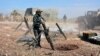 FILE - In this photo released by the Syrian official news agency SANA, Syrian army soldiers prepare to launch a mortar towards insurgents in the village of Kfar Nabuda, in the countryside of Hama province, Syria, May 11, 2019.