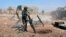 FILE - In this photo released by the Syrian official news agency SANA, Syrian army soldiers prepare to launch a mortar towards insurgents in the village of Kfar Nabuda, in the countryside of Hama province, Syria, May 11, 2019.