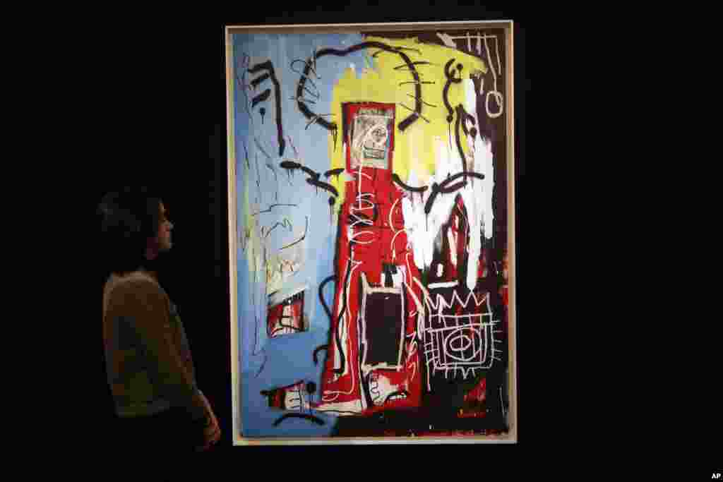 伦敦苏富比拍卖行的人员站在美国画家巴斯奎特（Jean-Michel Basquiat，有人翻译成巴斯奇亚）创作的油画《无题》（Untitled）旁边（2017年2月22日）。