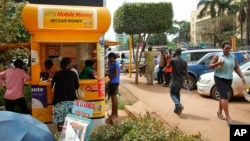 FILE - Ugandans use a mobile money point in Kampala, Uganda, Sept. 29, 2016. The country's Financial Intelligence Authority, set up to track illicit money flows, says it lacks resources to stop them.