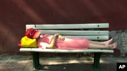 An unidentified girl takes a nap on a bench along the red walls next to Tiananmen Gate in Beijing Sunday, July 15, 2001. (AP Photo/Vincent Yu)