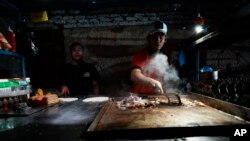 ຄົນ​ຂາຍ​ອາ​ຫານ​ຕາມ​ຖະ​ໜົນ​ກ​ະ​ກຽມ​ອາ​ຫານ​ດ້ວຍ​ໄຟ​ທີ່​ມາ​ຈາກ​ຈັກ​ປ້ຳ​ໄຟ​ຟ້າ, ເມືອງ ມານ​ຕາ, ເອ​ກົວ​ດໍ, 23 ກັ​ນ​ຍາ 2024.(AP Photo/Dolores Ochoa)