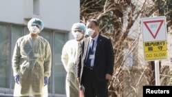 日本卫生官员戴着防疫口罩在东京的国立国际医疗研究中心等候从武汉撤回国的日本侨民。（2020年1月30日）
