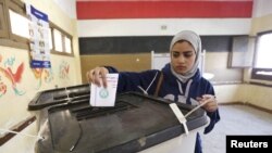 A woman casts her vote at a polling station during the second round of parliamentary elections in the Shubra area of Cairo, Egypt, Nov. 22, 2015. 